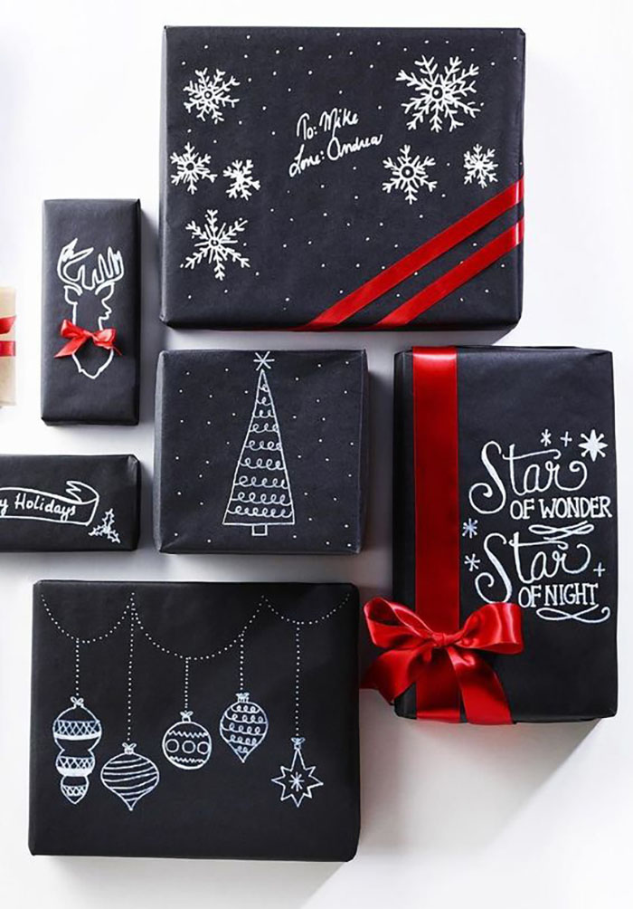 Unusual black wrapping paper decorated with drawings by a white pen and a red ribbon looks amazing on it.