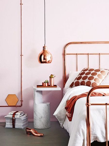 Rusty dotted cushion, copper celing lamp and pink wall color plus marbel nightstand is a surprising combination.